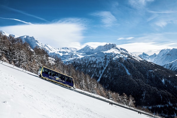 A train on a snowy mountain track with snow-covered mountains in the background.