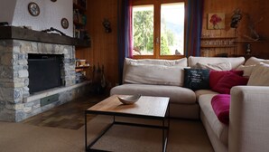 A cozy living room with a stone fireplace, a sofa, a coffee table, and a bookshelf.
