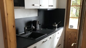 A compact kitchen with white cabinets, a black countertop, and a coffee maker.