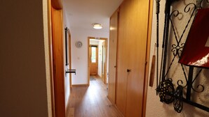 A hallway with wooden flooring, wooden doors, and a wall-mounted rack with items.