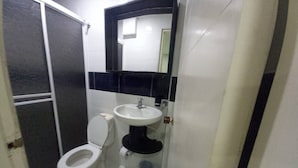 Een kleine badkamer met toilet, wastafel en spiegel.
