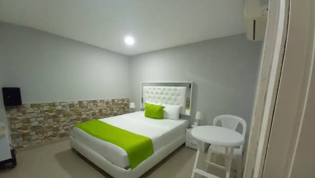 Een hotelkamer met een bed, een stoel en een klein tafeltje.
