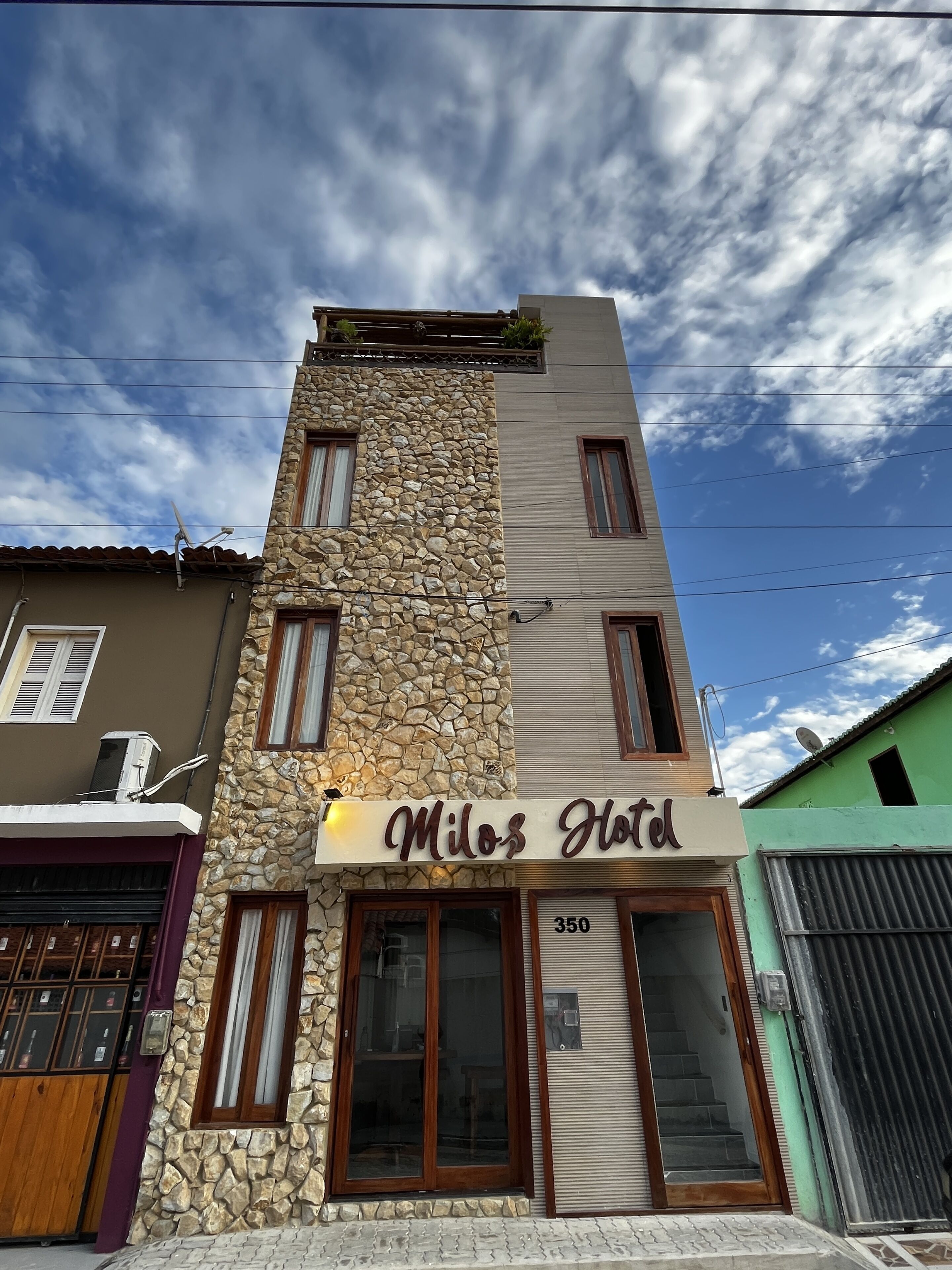 Un hôtel appelé Milos Hotel, doté d’une façade en pierre et de nombreuses fenêtres.