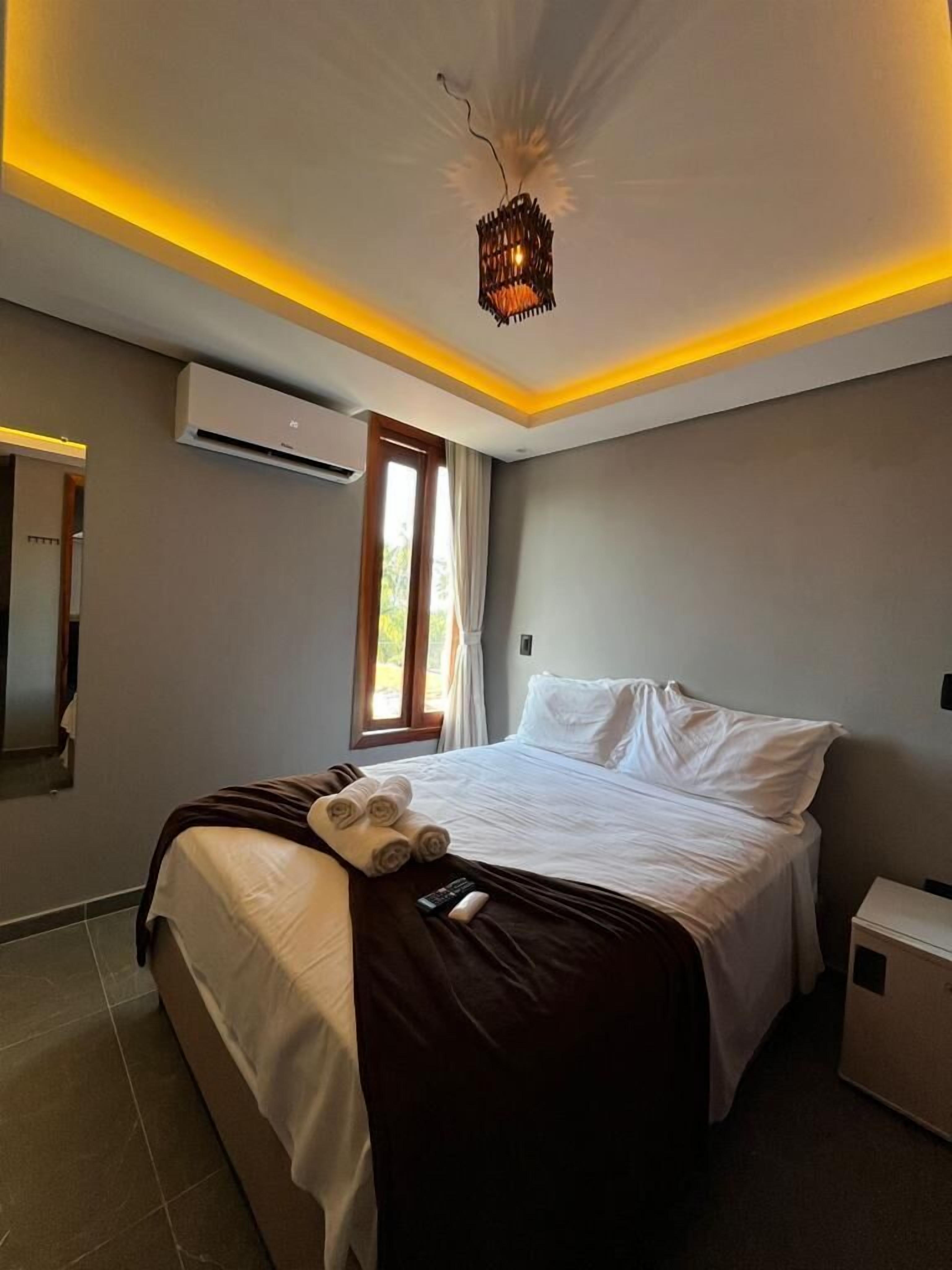 Ein modernes Hotelzimmer mit einem großen Bett, einer Deckenleuchte und einer Klimaanlage.