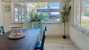 Un comedor con mesa de madera, sillas, un centro de mesa decorativo y un ventanal con vistas al exterior.