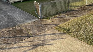 Een motel met een lang, laag gebouw, een overdekte veranda en een omheinde tuin.