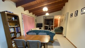 Een eethoek met een houten tafel en stoelen, een boekenkast en een blauwe bank.