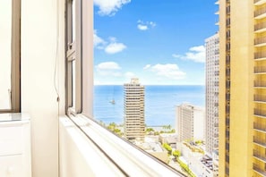 Um edifício alto com vista para o oceano e outros edifícios.
