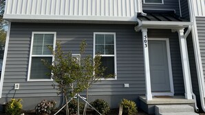 A multi-story residential building with a gray exterior and white trim. It features multiple windows with white frames and a visible door number '503'. - ViBe District Retreat #2 (Virginia Beach)