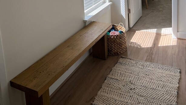 A hallway with a wooden bench, a woven rug, and a round mirror on the wall. - ViBe District Retreat #2 (Virginia Beach)
