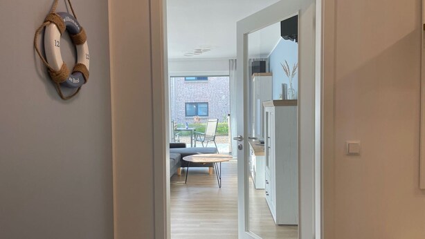 A modern interior with a doorway leading to a dining area and a kitchen. - Strandwiese - Ankerplatz - Ankerplatz - Strandnah... Wellenrauschen Inklusive! (Dahme)