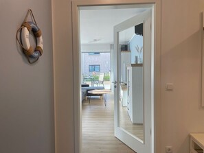 A modern interior with a doorway leading to a dining area and a kitchen. - Strandwiese - Ankerplatz - Ankerplatz - Strandnah... Wellenrauschen Inklusive! (Dahme)