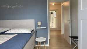 A bedroom with a bed, bedside table, and a small stool. - Strandwiese - Ankerplatz - Ankerplatz - Strandnah... Wellenrauschen Inklusive! (Dahme)