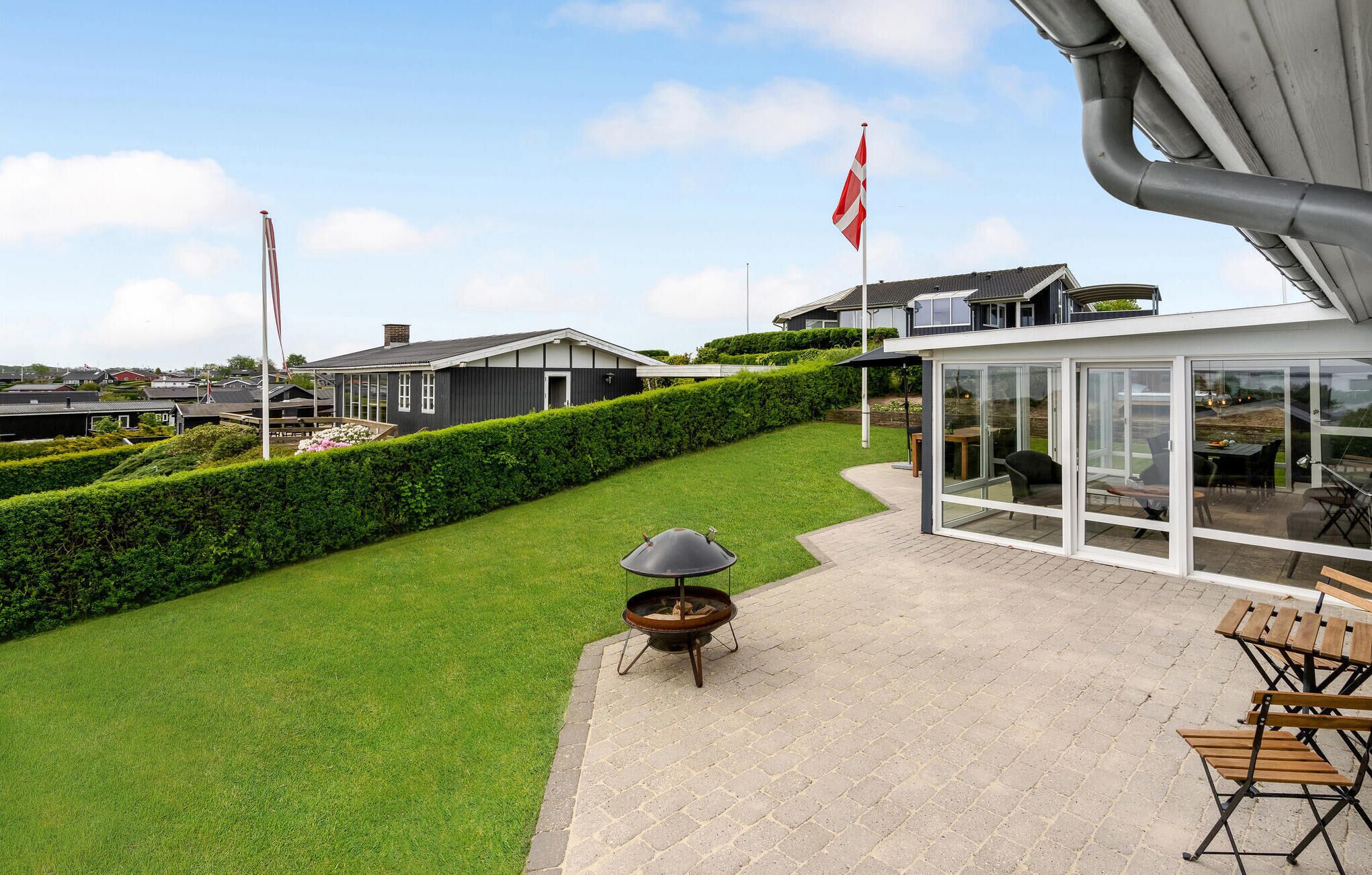 A modern outdoor patio with a grill, seating area, and a view of the surrounding neighborhood.