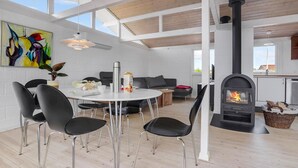 En moderne stue med spiseplads, sofa, pejs og et stort vindue.