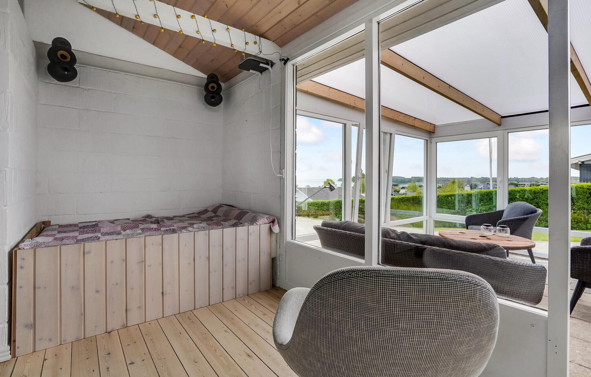 A sunroom with a wooden floor, a seating area with a sofa and chairs, and a view of the outdoors.