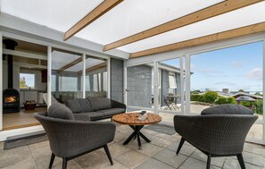 An open-plan living area with a fireplace, grey sofas, and a round wooden table. - 2 bedroom lovely home in Hejls (Hejls)
