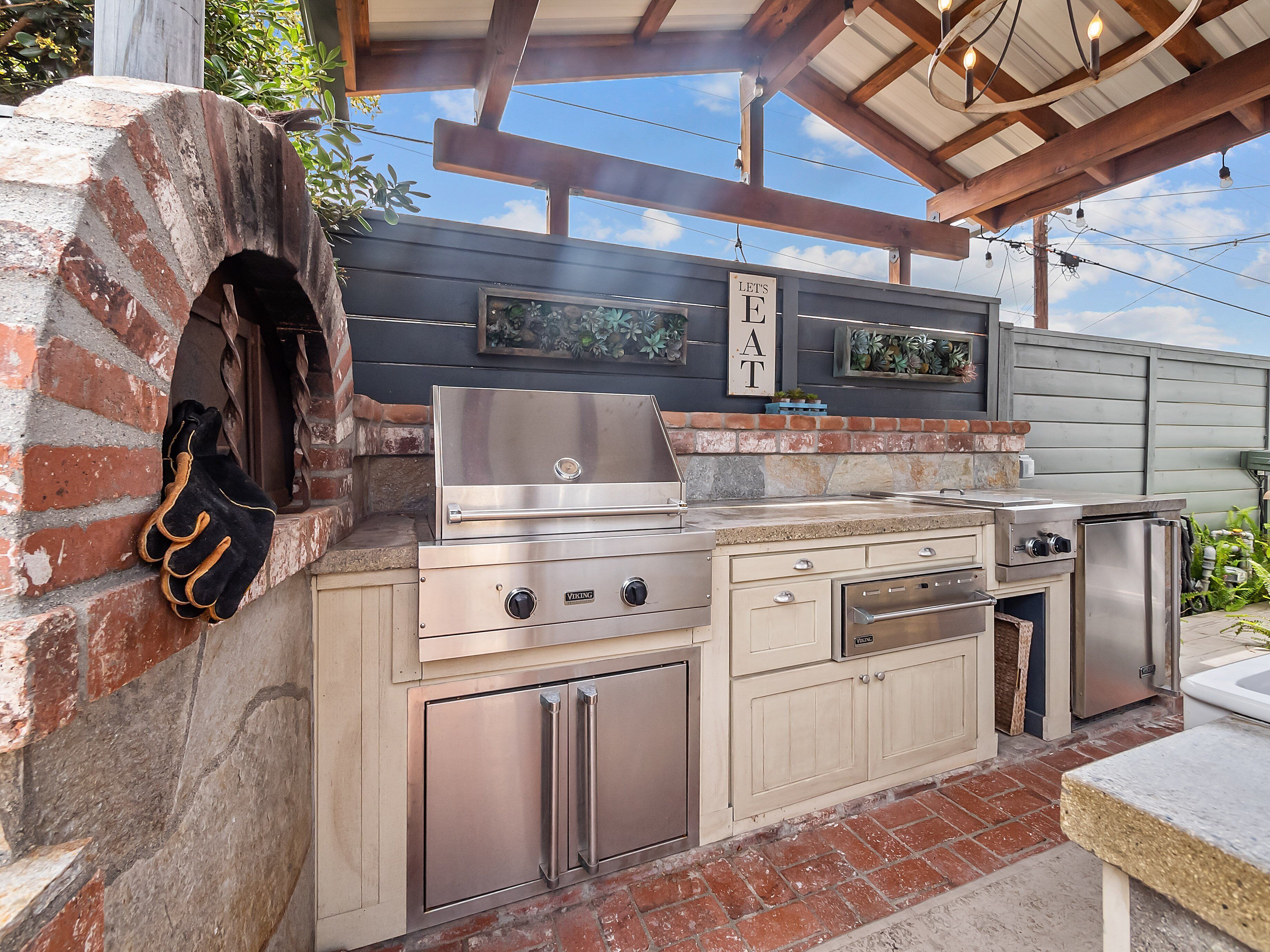 A kitchen with a brick oven, stainless steel appliances, and a sign that says "LET'S EAT".