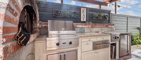 A kitchen with a brick oven, stainless steel appliances, and a sign that says "LET'S EAT".
