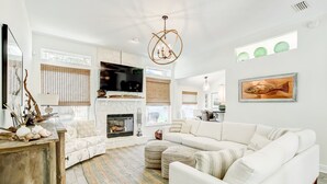 Una sala de estar moderna con un sofá blanco, una chimenea y un televisor grande.