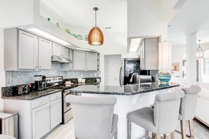A modern kitchen with white cabinets, a granite countertop, and a central island with bar stools.