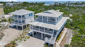 Una casa costera con dos estructuras principales, un balcón y vista al océano.