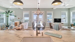 Una cocina moderna con una isla central, un comedor con una mesa alta y un gran ventanal con vistas a la ciudad.