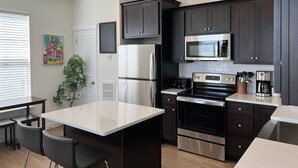 Una cocina moderna con armarios oscuros, electrodomésticos de acero inoxidable y una isla central.
