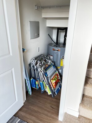Un espace de rangement compact doté d’une porte blanche, d’un petit meuble utilitaire et d’une collection de parapluies et de cannes colorés.