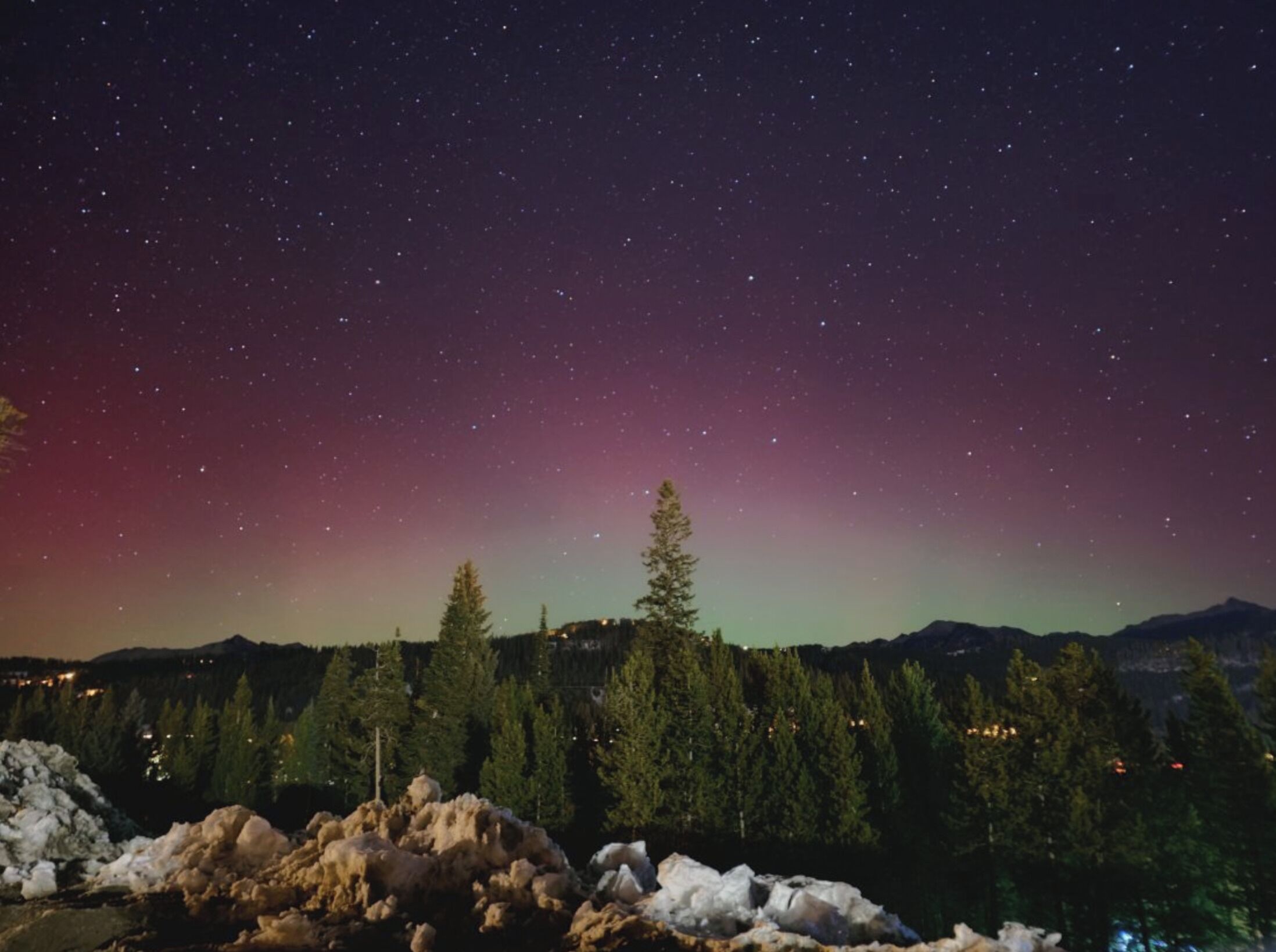 Cielo nocturno con estrellas y una aurora visible.