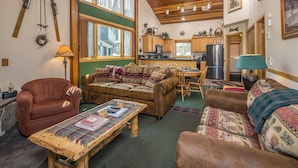 Una sala de estar acogedora con chimenea, un comedor y una cocina con armarios de madera y un refrigerador.