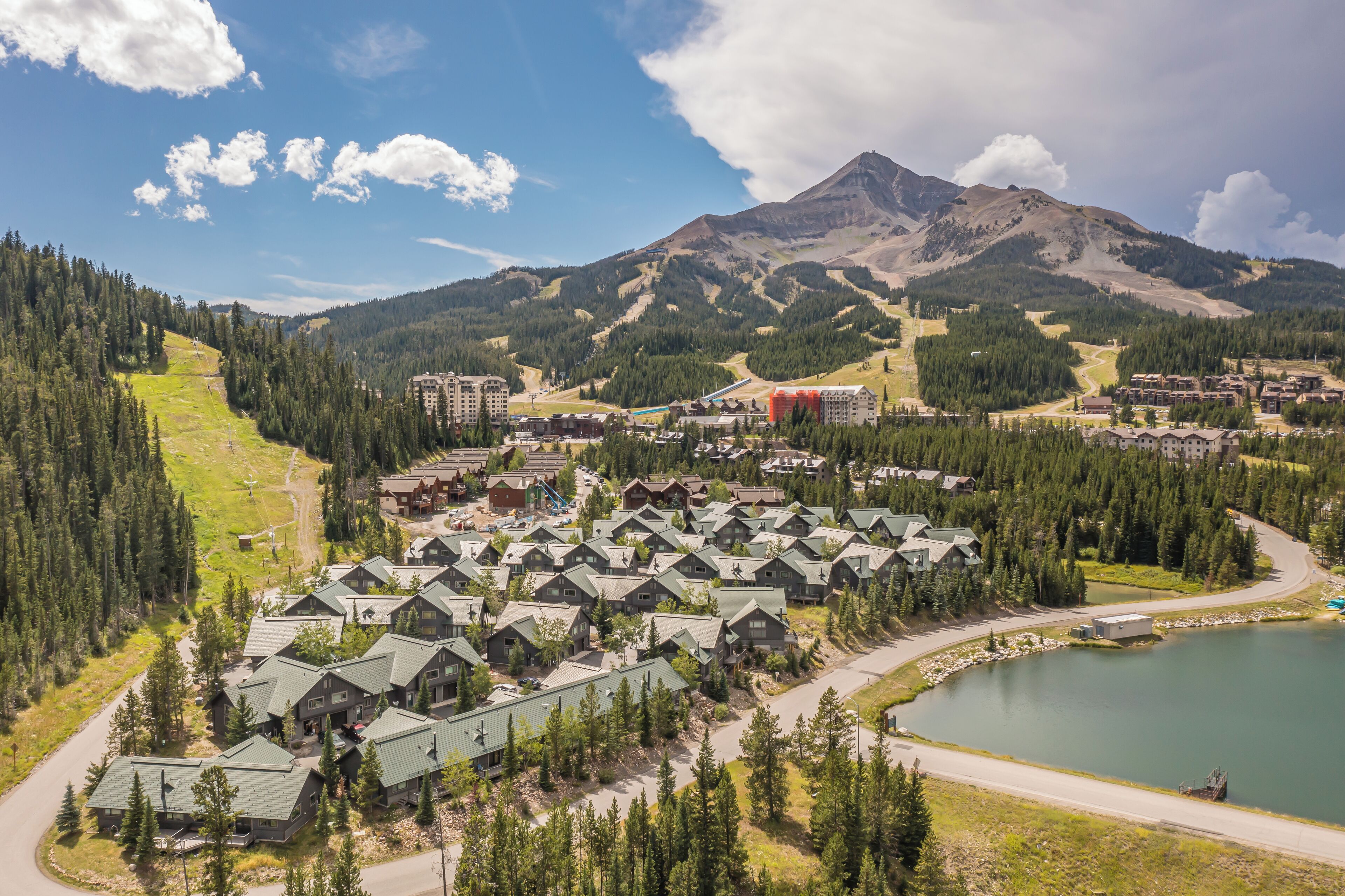 Un resort con diversi edifici in stile chalet, una seggiovia e un lago.