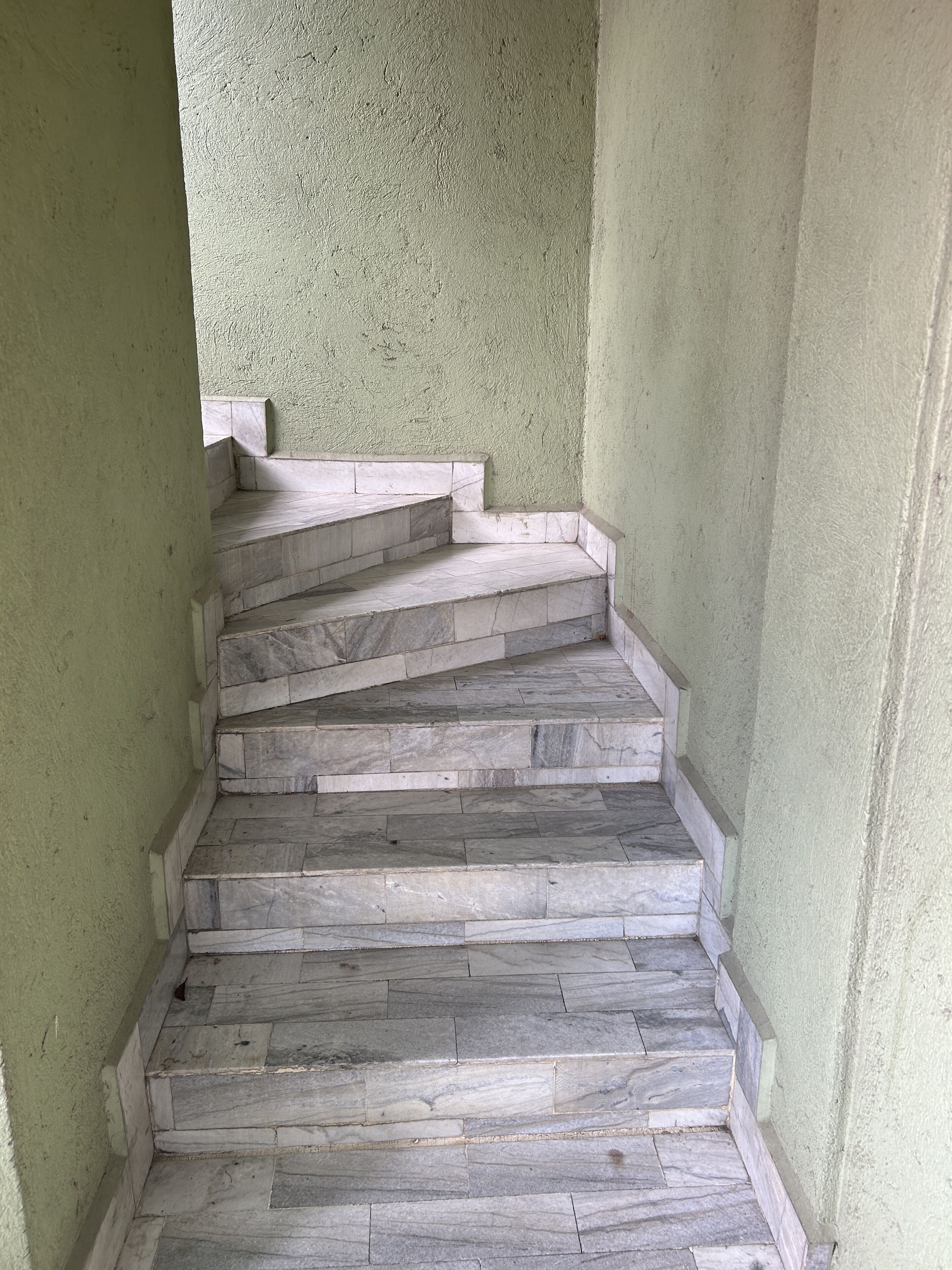 A staircase with stone steps and a green wall.