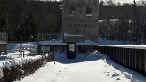 Eine Betonkonstruktion mit dem Schriftzug "Victoria Dam" und einer amerikanischen Flagge, umgeben von Schnee und Bäumen.