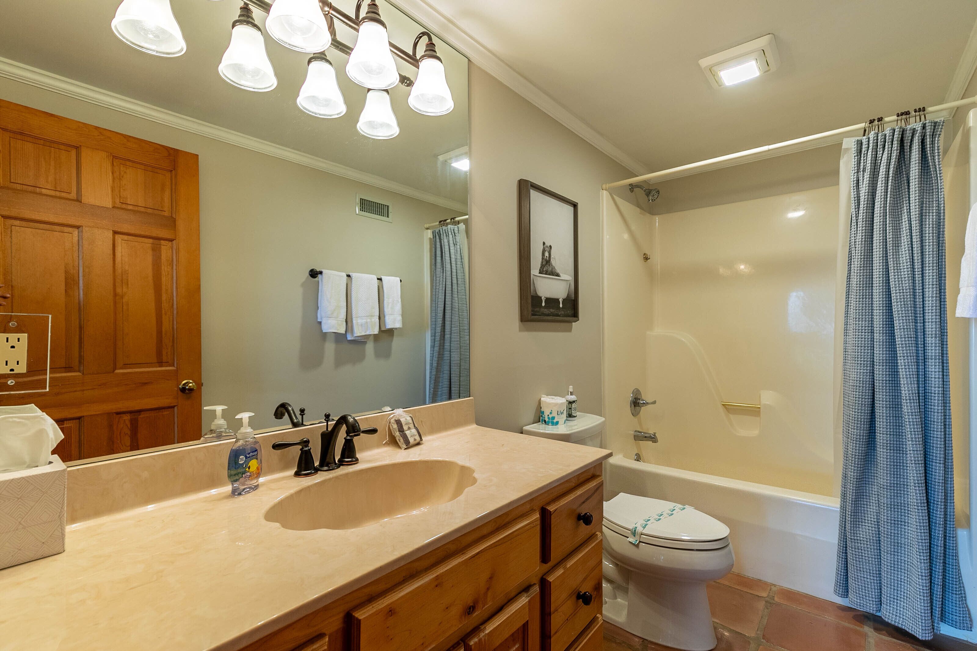 Un baño con tocador de madera, lavamanos, inodoro y bañera.
