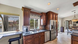 Una cucina moderna con mobili in legno scuro, elettrodomestici in acciaio inossidabile e un'ampia finestra che offre vista sull'esterno.