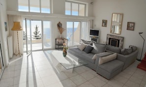 Relax in this stylish living room with a sofa, coffee table, and fireplace, offering a view of the sea from the balcony.