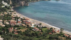 A coastal town with buildings along the beach, a clear view of the sea, and a hilly backdrop. - Villa Alibertini With sea View (Corfu)