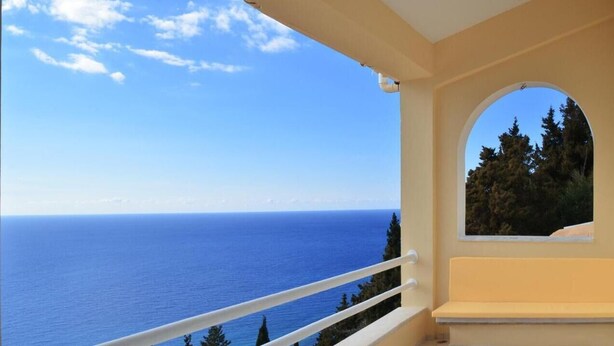 A balcony with a clear view of the sea and a forested area. - Villa Alibertini With sea View (Corfu)