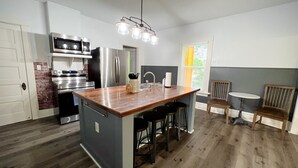 A modern kitchen with a central island, stainless steel appliances, and a dining area with a small table and chairs. - Townside@LavaHotSprings (Lava Hot Springs)