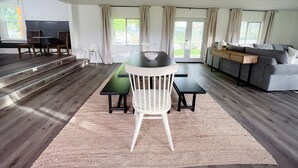 A spacious living room with a dining area, large windows, and a staircase leading to an upper level. - Townside@LavaHotSprings (Lava Hot Springs)