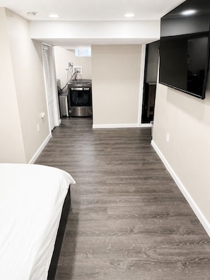 A bedroom with a bed, a TV mounted on the wall, and a laundry area with appliances. - Tranquil Modern Townhome (East Orange)