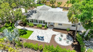 A house with a patio area featuring a seating arrangement and a small garden. - Siesta Dolce | Private Pool, Kayaks and Putting Green (Siesta Key)