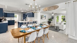 A modern kitchen with dark blue cabinets, a wooden dining table set for six, and a chandelier. - Siesta Dolce | Private Pool, Kayaks and Putting Green (Siesta Key)