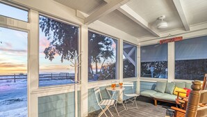 Un espace extérieur aménagé, abrité et doté de sièges, avec vue sur la plage, comprenant une table avec des chaises et un canapé.