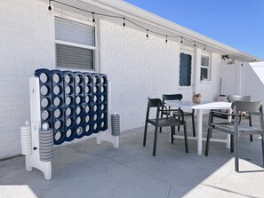 A patio with a white brick wall, a table with chairs, and a decorative blue and white structure.