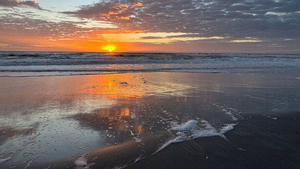 A beach with a sunset, waves, and a clear sky. - The Coconut (Cocoa Beach)