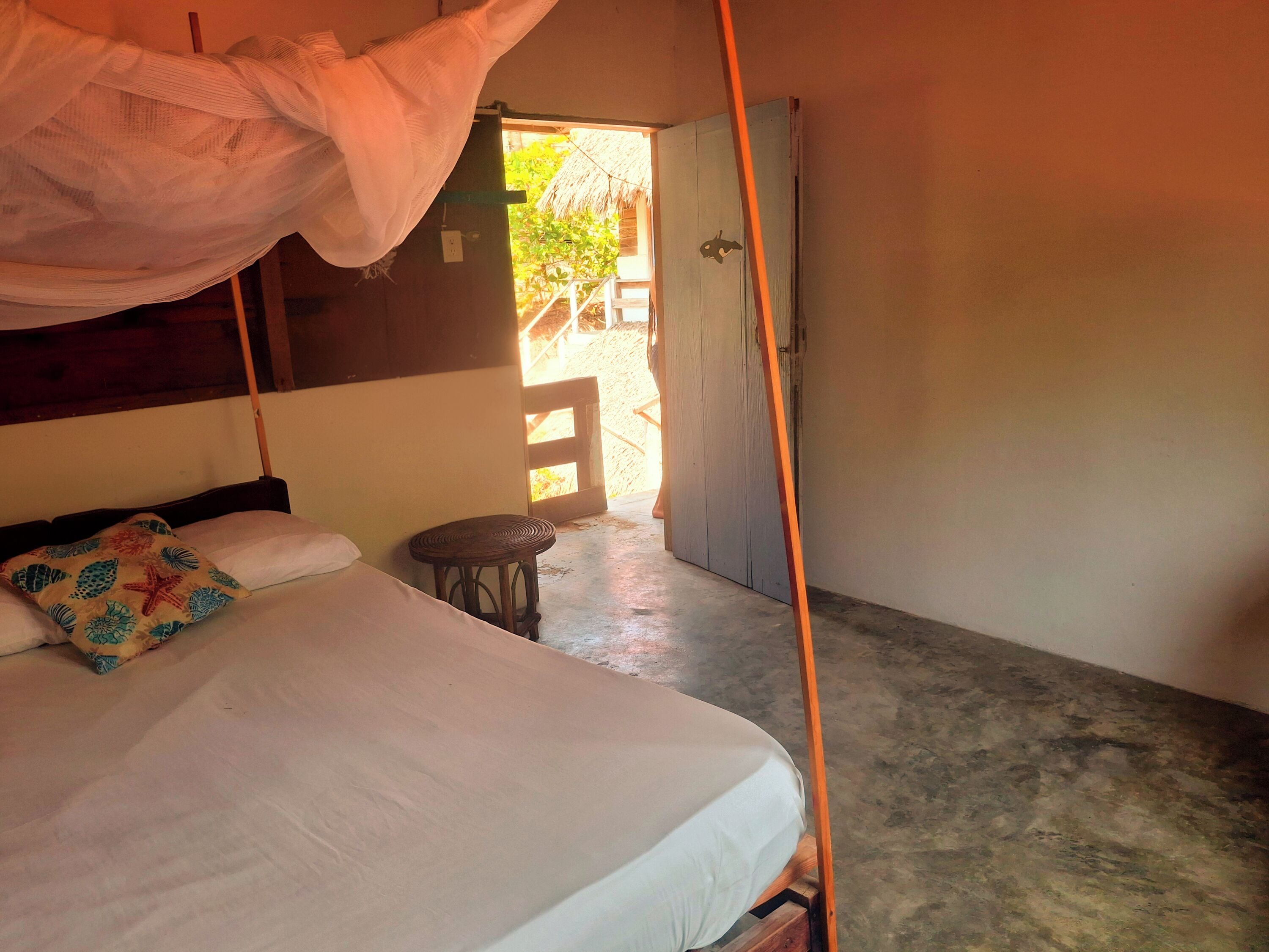 A room with a bed, a small round table, and a door leading outside.