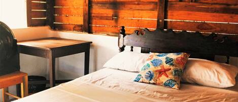 Una habitación con cama, cabecera de madera, mesita de noche y mosquitero sobre la cama.