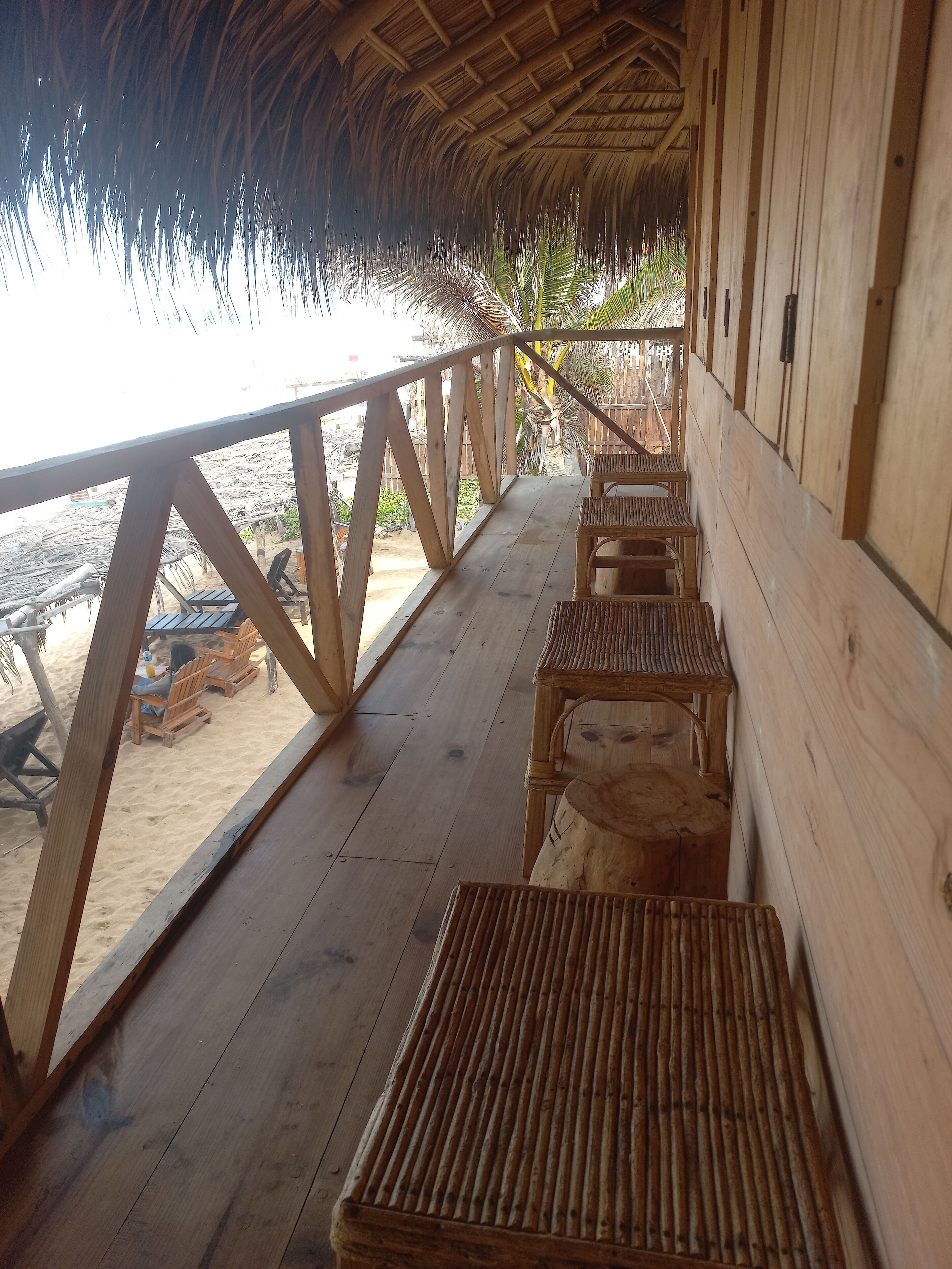 A wooden deck with a railing overlooking a beach.
